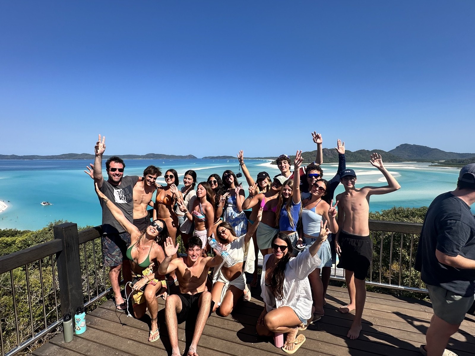 Turma de estudantes STB no mirante de Hill Inlet, com a areia branca e a água turquesa de Whitehaven Beach ao fundo