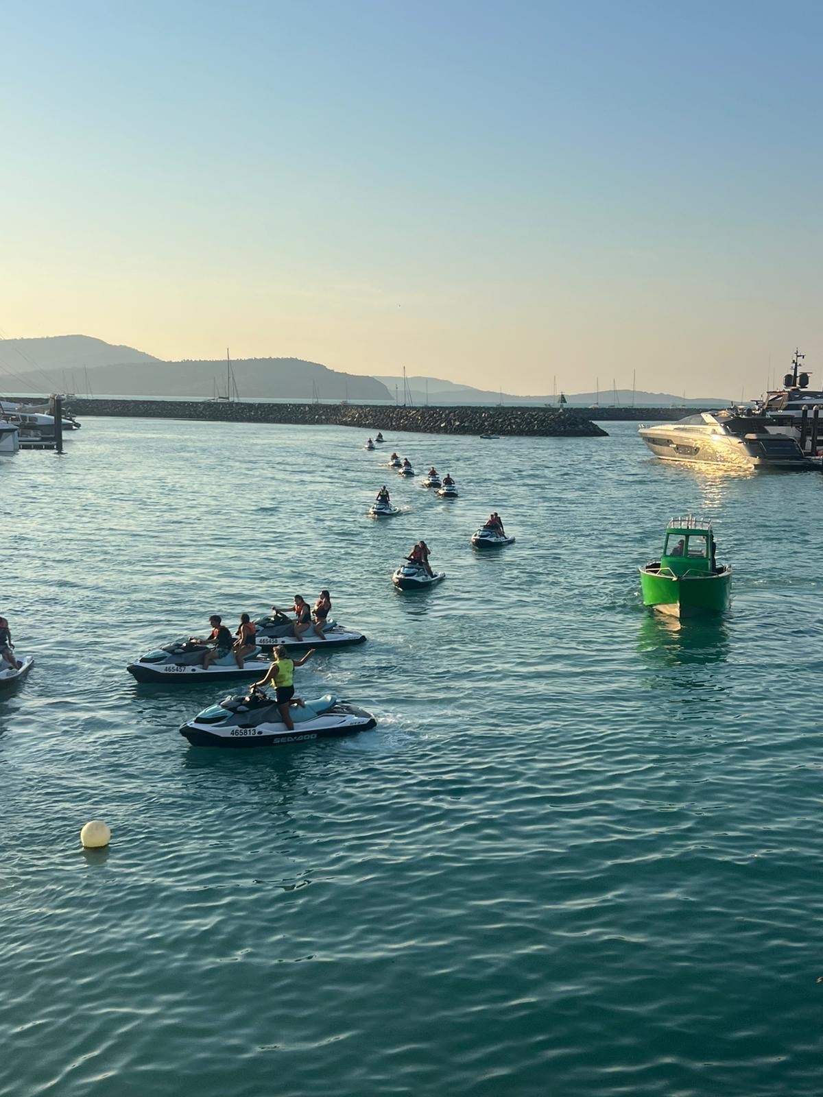 Estudantes em jet skis ao pôr do sol na baía de Airlie Beach